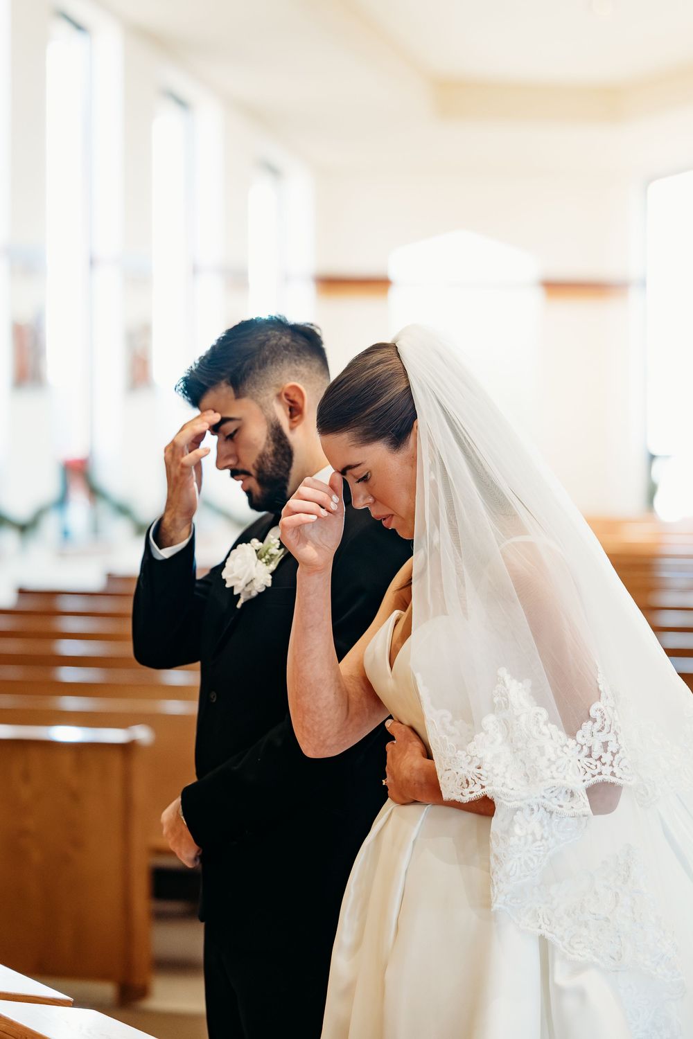 An emotional first look moment between a bride and groom in a bright church sanctuary.