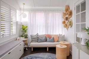 Bright and airy bedroom with white bedding, sheer curtains, plants, and natural light streaming through windows.