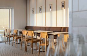 Modern restaurant interior with wooden chairs and bench seating along wall.