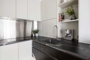Contemporary white kitchen with black marble counters and built-in appliances.