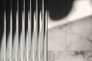 Abstract architectural detail showing vertical glass panels with soft lighting and shadow.