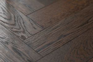 Macro shot of dark wood flooring showing grain texture and plank joints.
