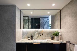 Modern bathroom vanity with large mirror, marble countertop and recessed lighting.