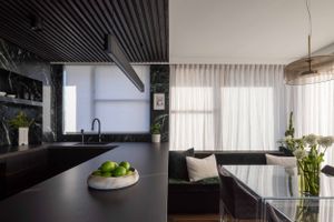Contemporary kitchen featuring black countertops, white curtains and natural lighting.