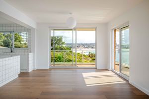 Modern empty room interior with floor-to-ceiling windows, white walls, and hardwood flooring offering panoramic views.