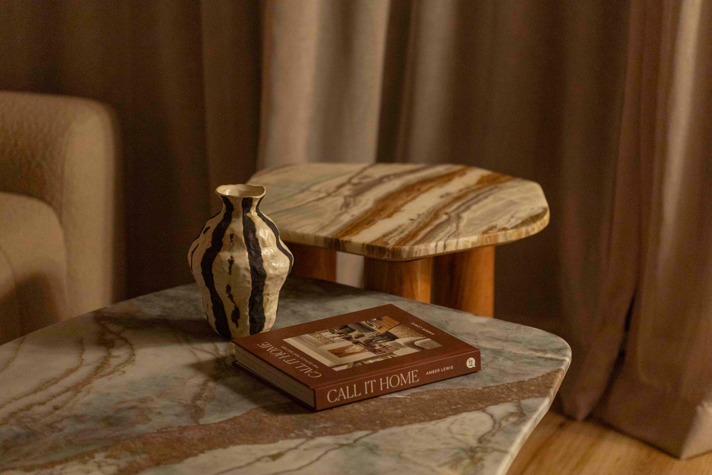 Stylish marble table with decorative vase and book in warm ambient lighting.