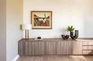 Contemporary wooden sideboard with framed artwork and decorative pieces in minimal interior.