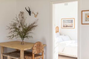 Minimalist room interior with antler decor and wooden furniture overlooking bedroom.