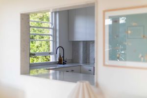 Bright kitchen pass-through window with modern black faucet and natural lighting.