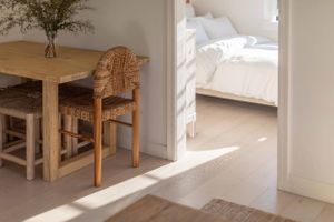 Sunlit interior with wooden dining furniture casting shadows on light hardwood flooring.