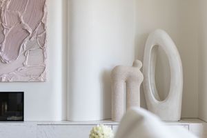 A collection of white plaster decorative wall sculptures and architectural elements displayed in a gallery setting.