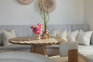 Cozy dining nook with round wooden table, built-in bench seating, and natural light streaming through windows.