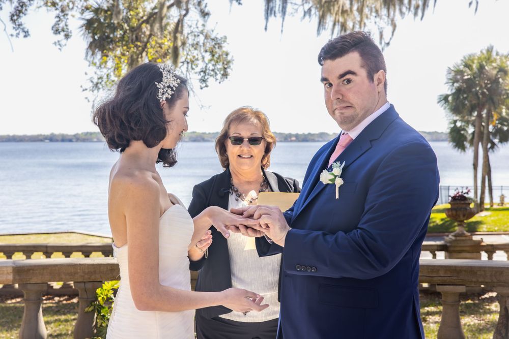 An outdoor wedding ceremony taking place by waterfront with Spanish moss trees.