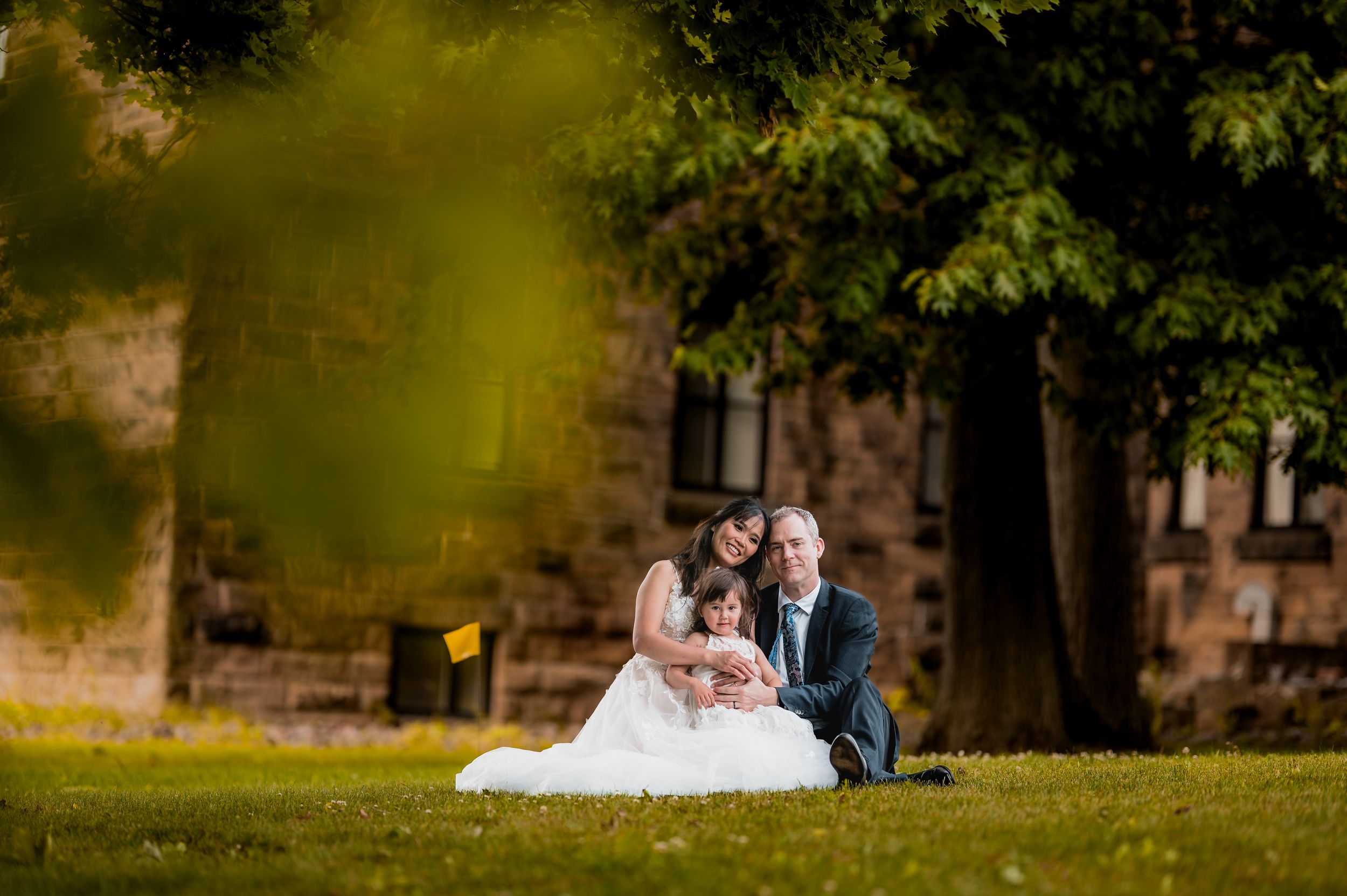 Couple shares an intimate moment on grassy grounds with a castle-like building in background.  New Brunswick Wedding photographer