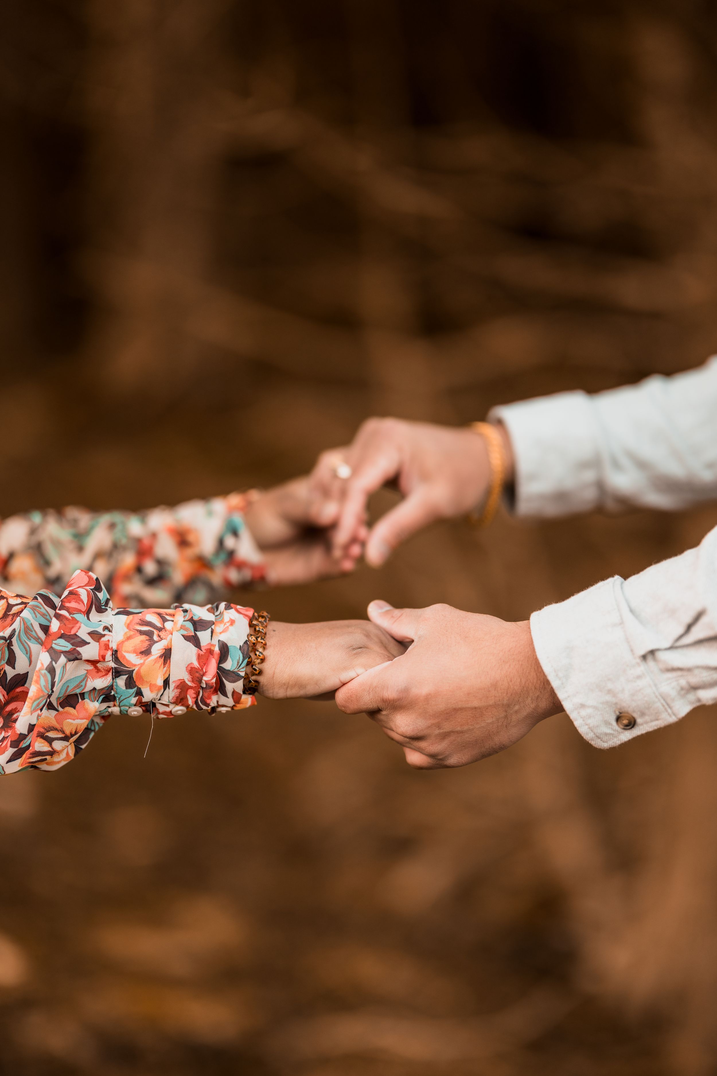 Close-up of hands reaching towards each other against a blurred forest background.  New Brunswick Wedding photographer