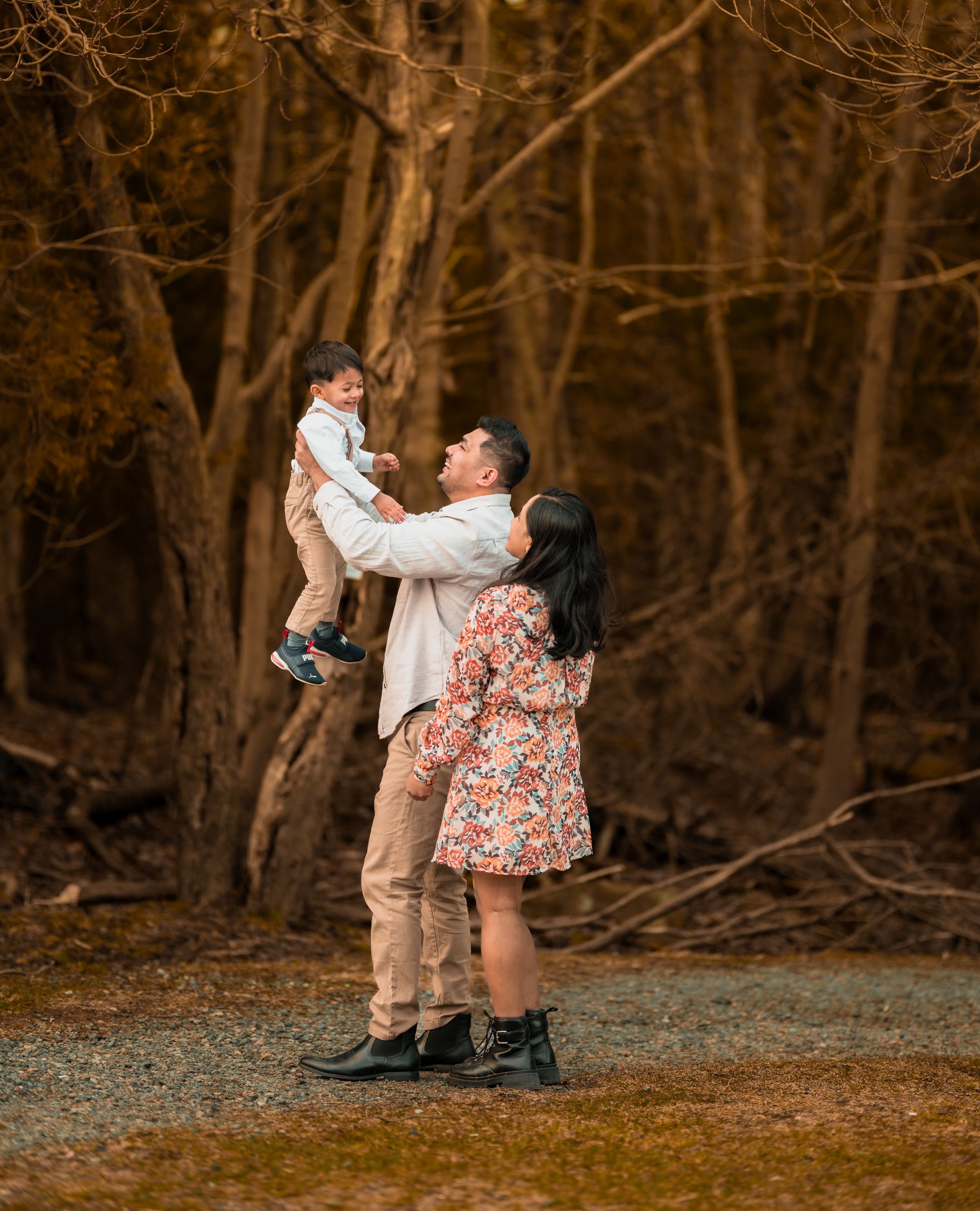 Playful family moment captured in a wooded area with warm autumn lighting.  New Brunswick Wedding photographer