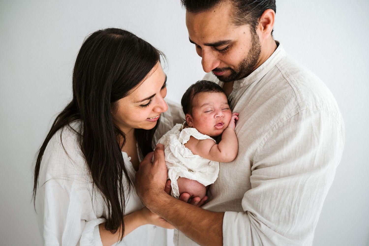 Intimate newborn family photography session with white backdrop and natural styling.