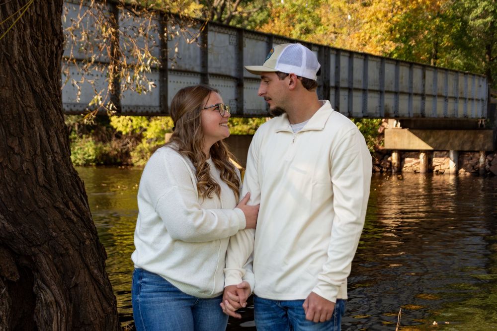 Romantic couple in white outfits sharing intimate moments by a lake during golden hour photography session.