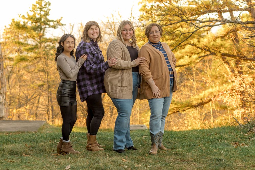 Family members walking through a golden autumn field during sunset, showing only their legs and feet.