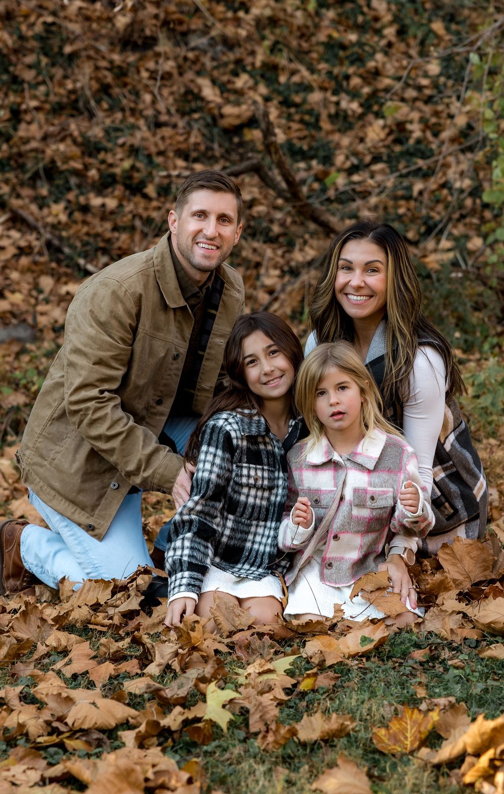 Family lifestyle portrait outdoors laying in fallen autumn leaves during a fall photo session.