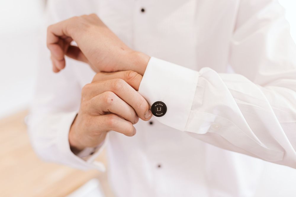 Close-up of hands adjusting white formal shirt cuffs.