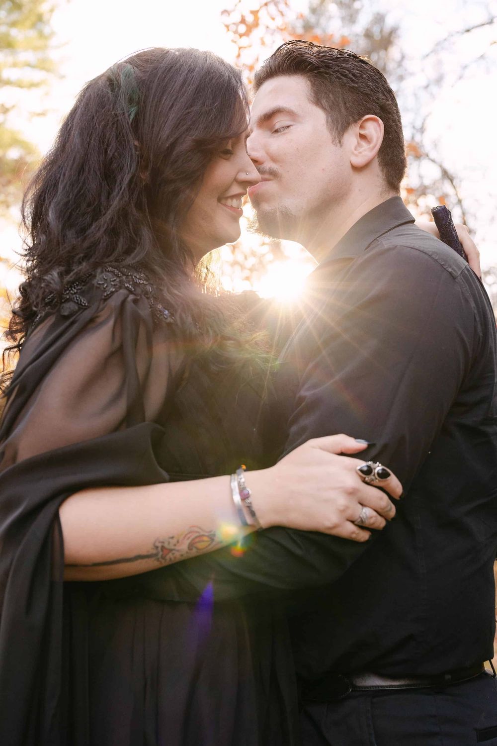 A romantic silhouette showing a couple embracing and kissing at sunset with a golden sun flare behind them.
