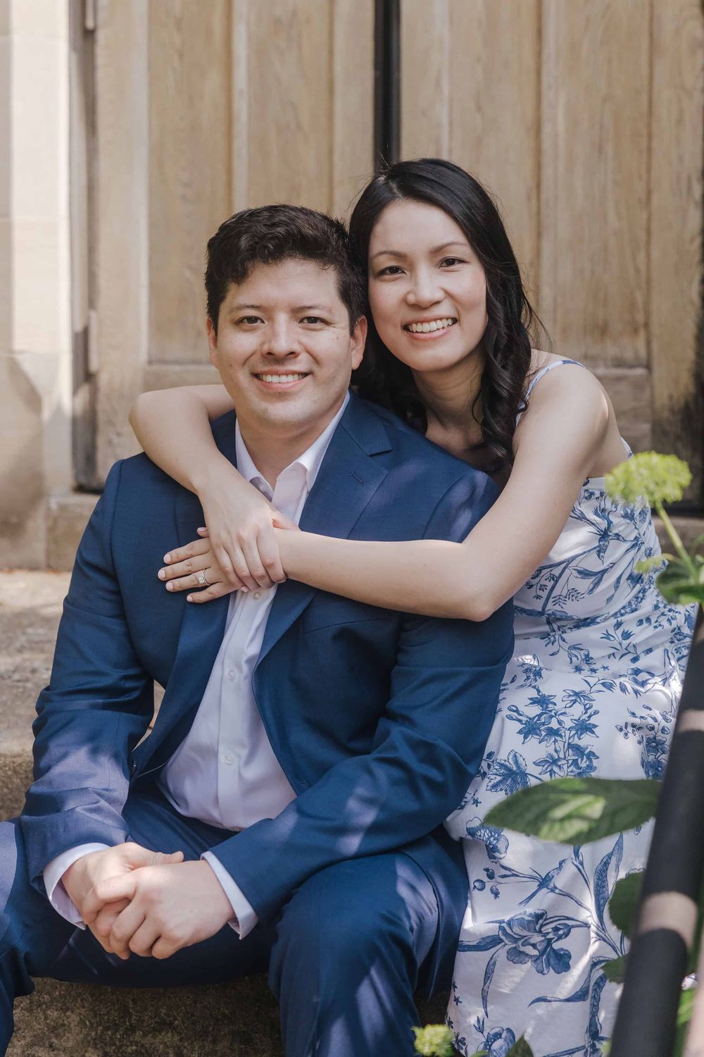 A couple sits together on wooden steps wearing coordinated navy and white outfits.