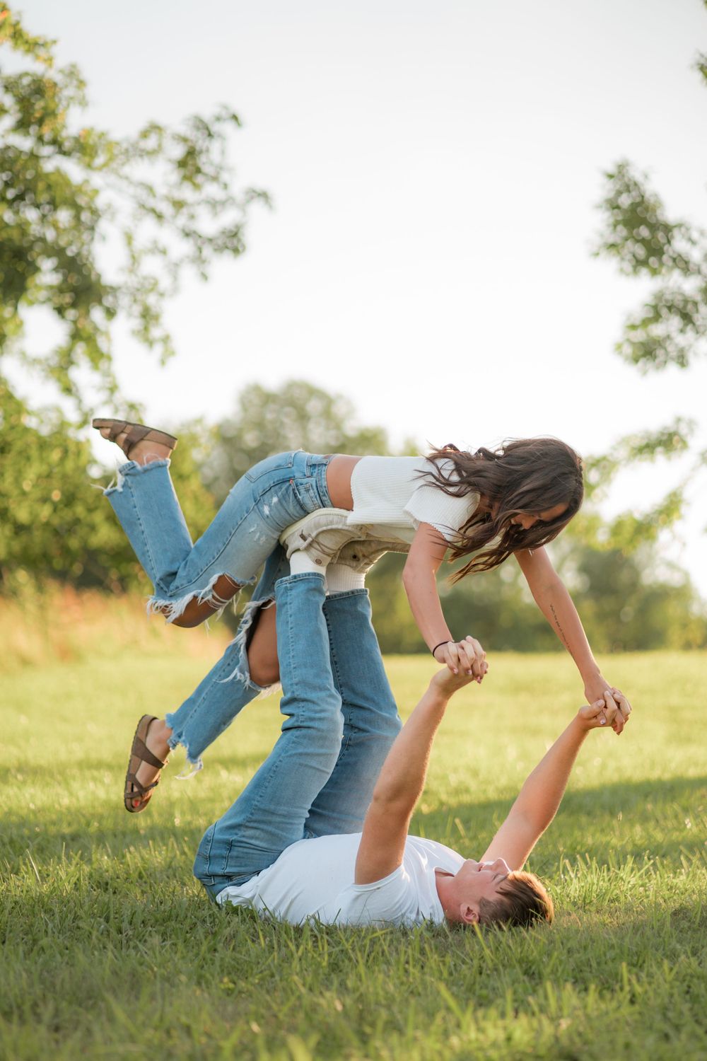 A playful moment in a grassy field with one person lifting another in the air.