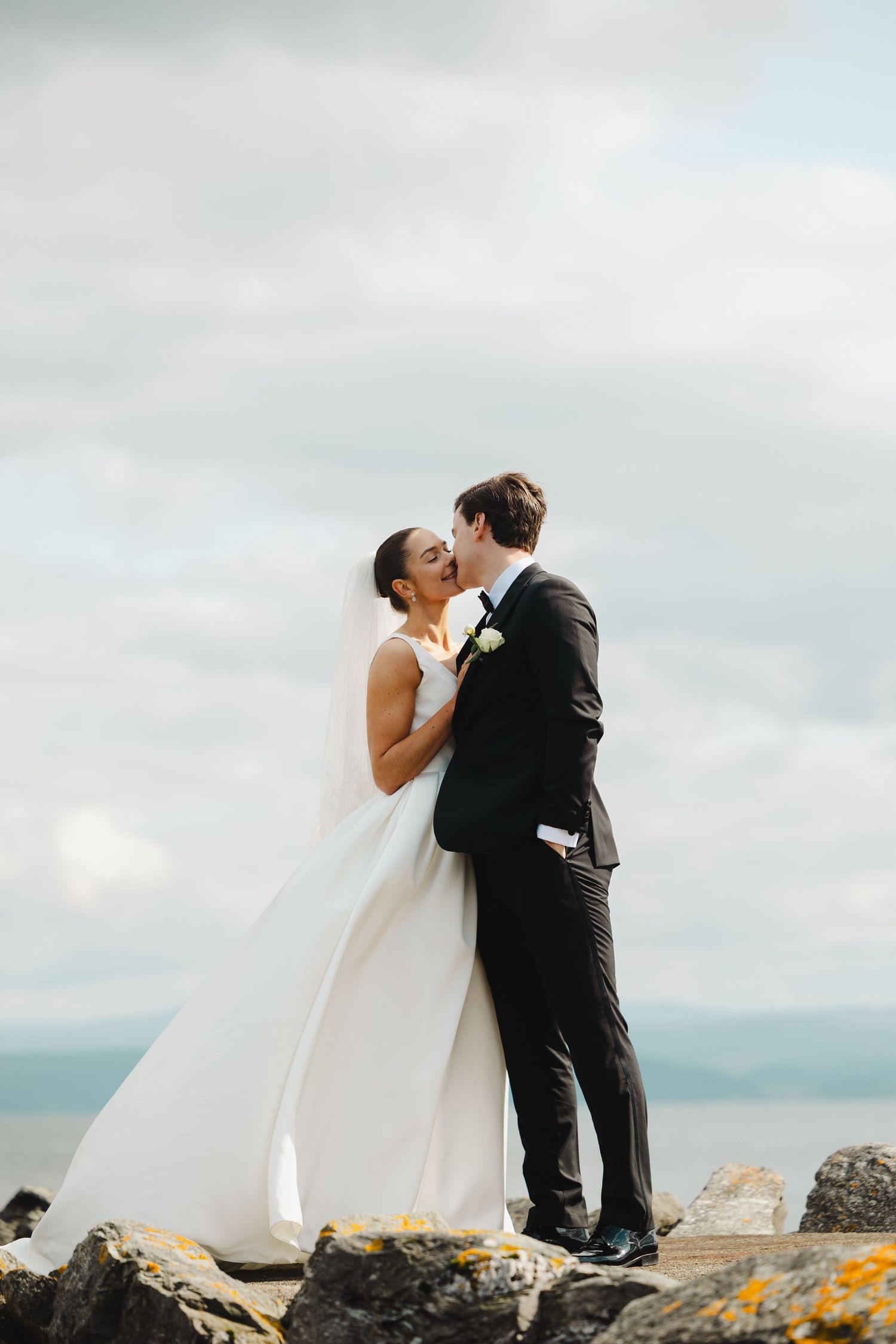 A windy mountaintop wedding moment captured with flowing dress and stunning mountain vistas.