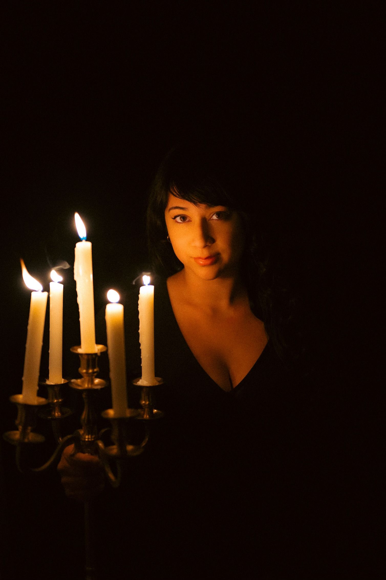 A series of dark atmospheric photos showing lit candles casting shadows and warm light in a moody setting.