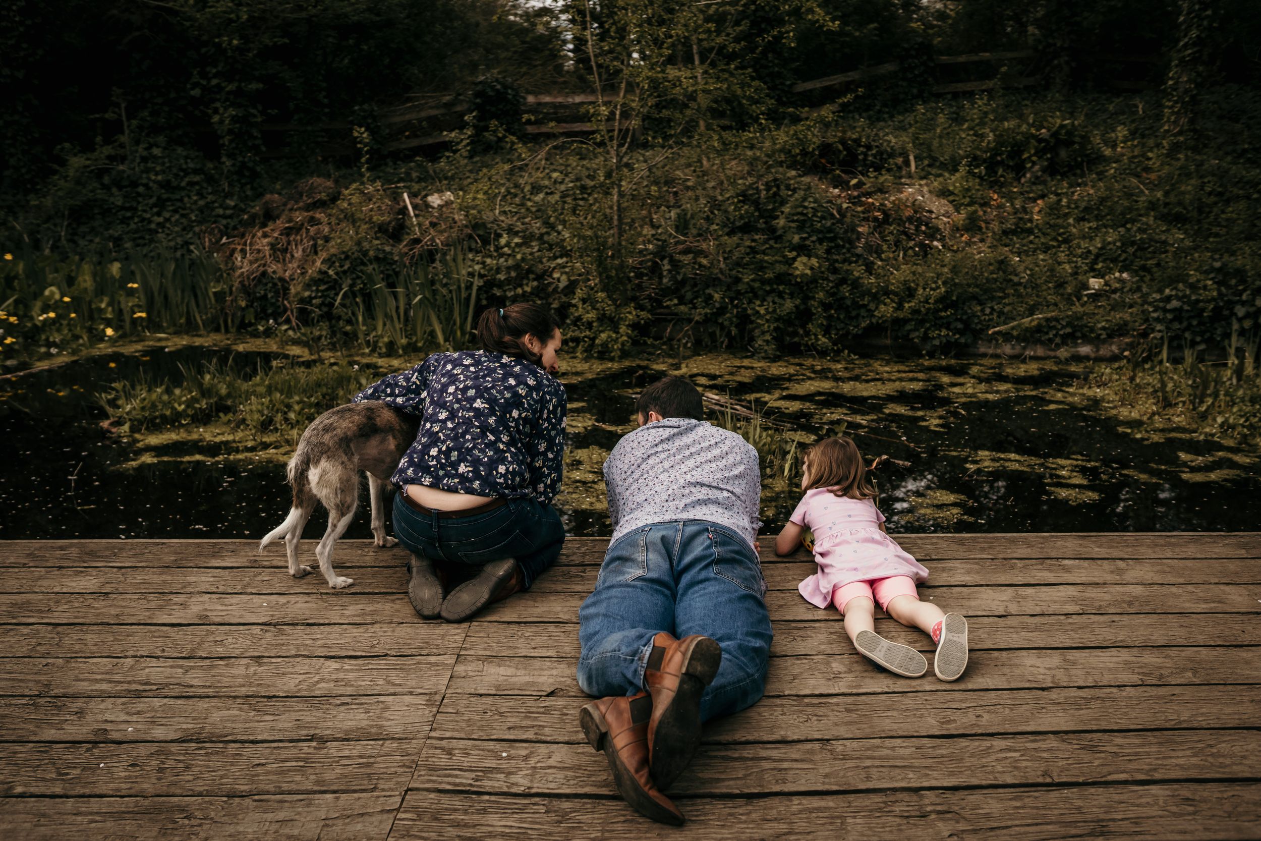 the backs of a family all looking into a pond together