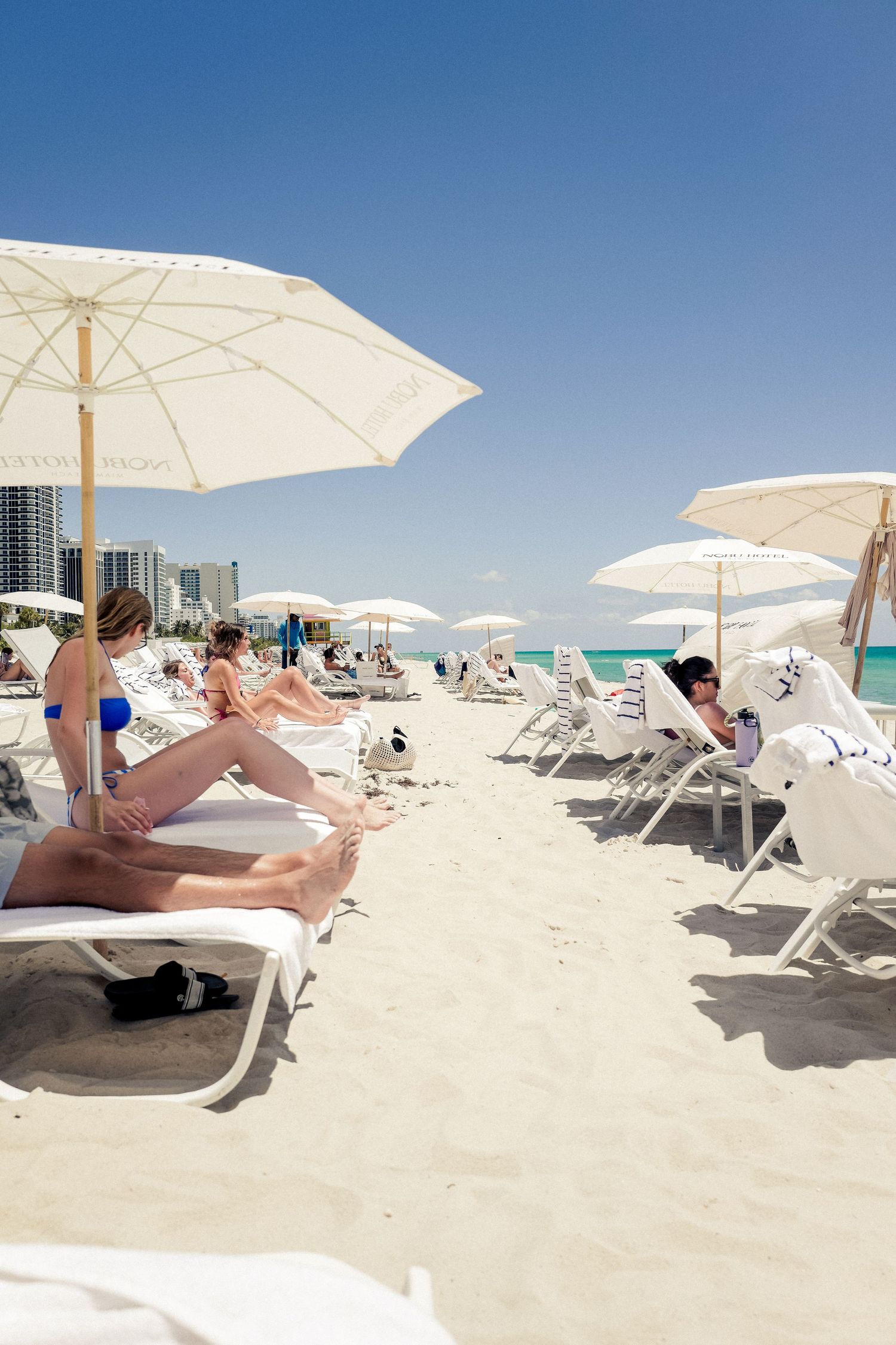 White umbrellas and lounge chairs line a pristine beach with turquoise waters.