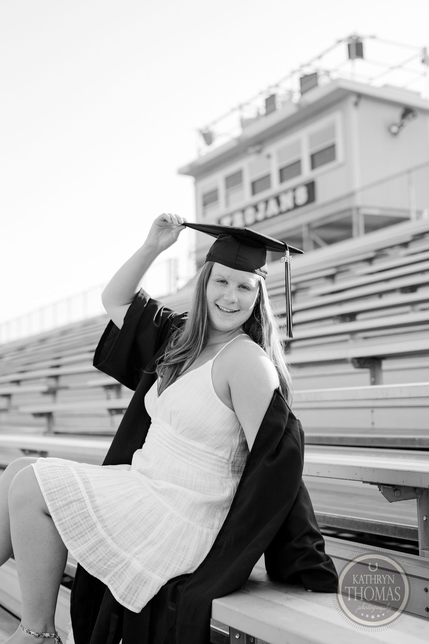 Black and white graduation portrait captured on stadium bleachers.