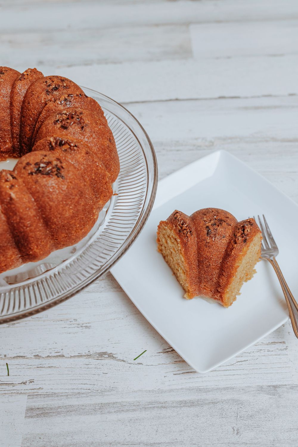 Freshly baked bundt cake with a slice cut and served on a white plate.