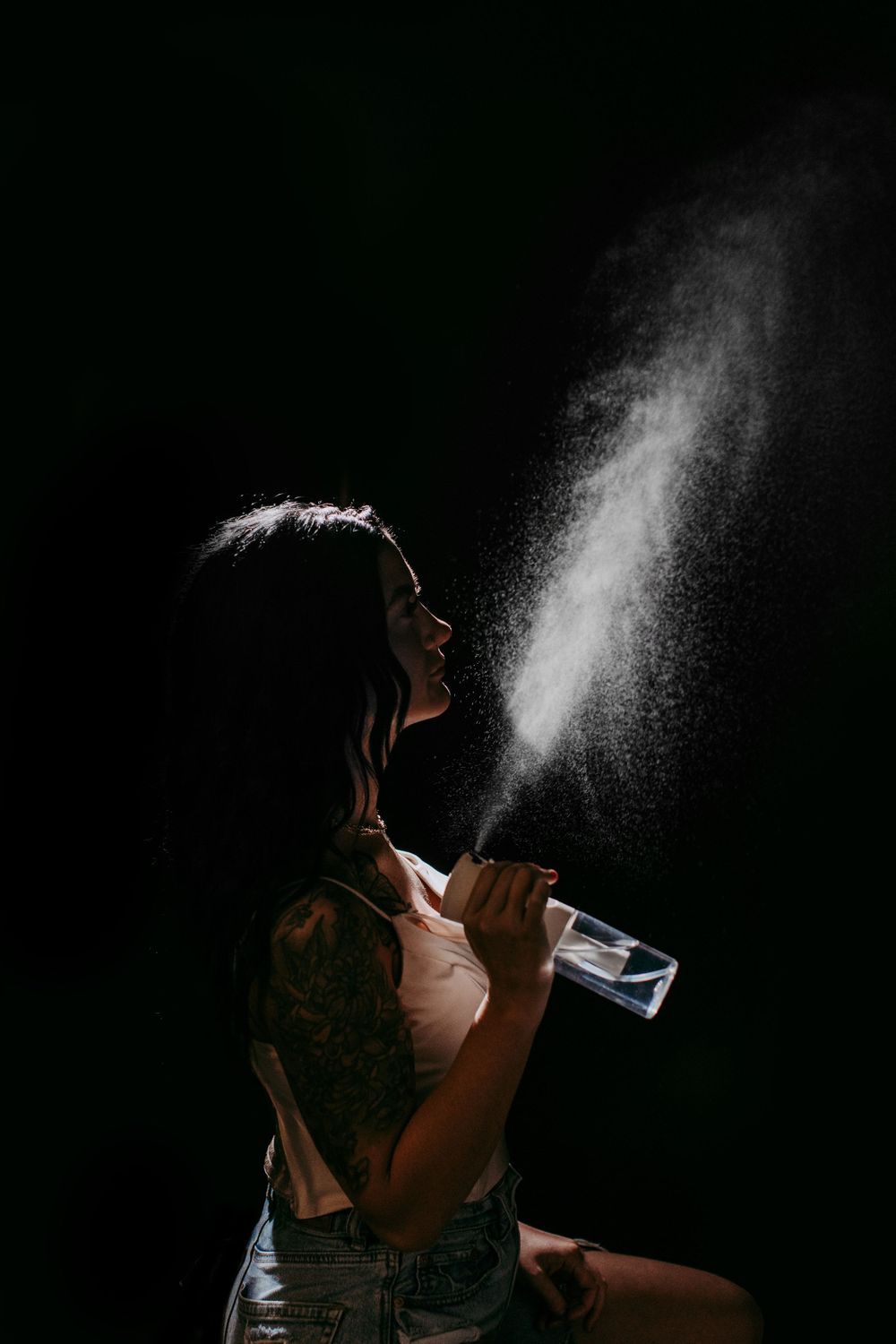 A dramatic silhouette photo of water being sprayed in the dark.