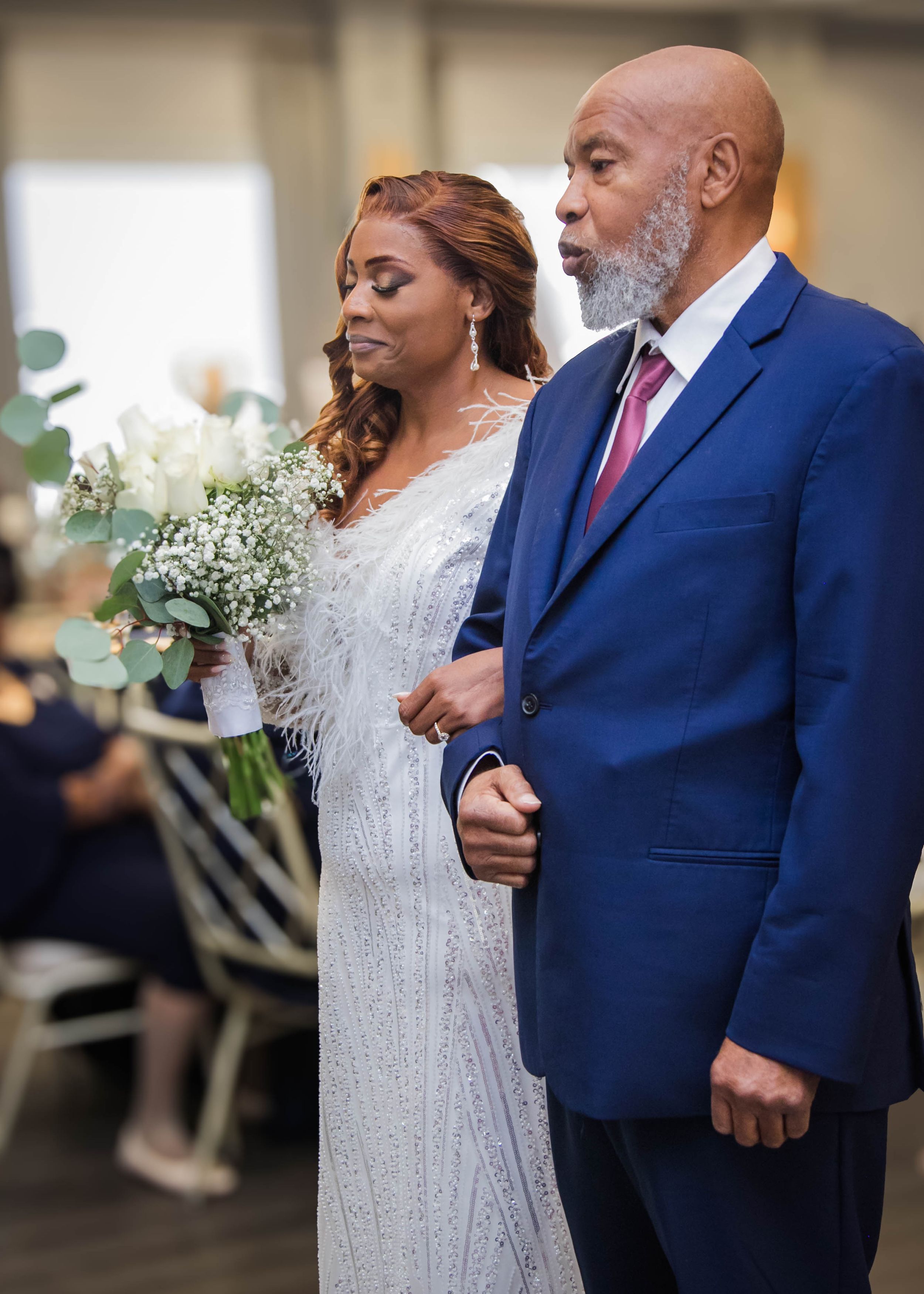 Emotional wedding moment captured as couple in formal attire walks down aisle.
