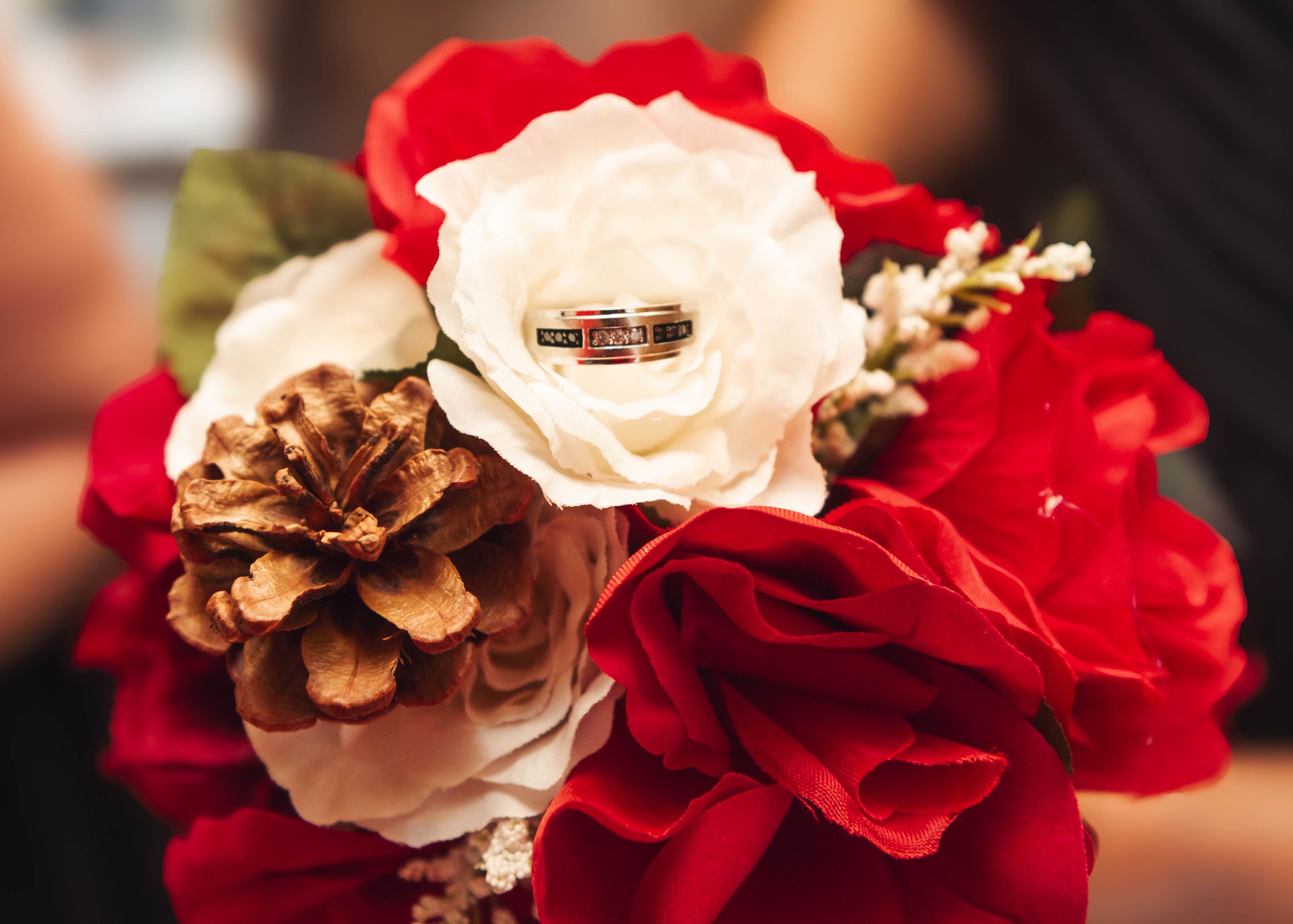 Wedding rings nestled among red and white roses in an artistic close-up shot.