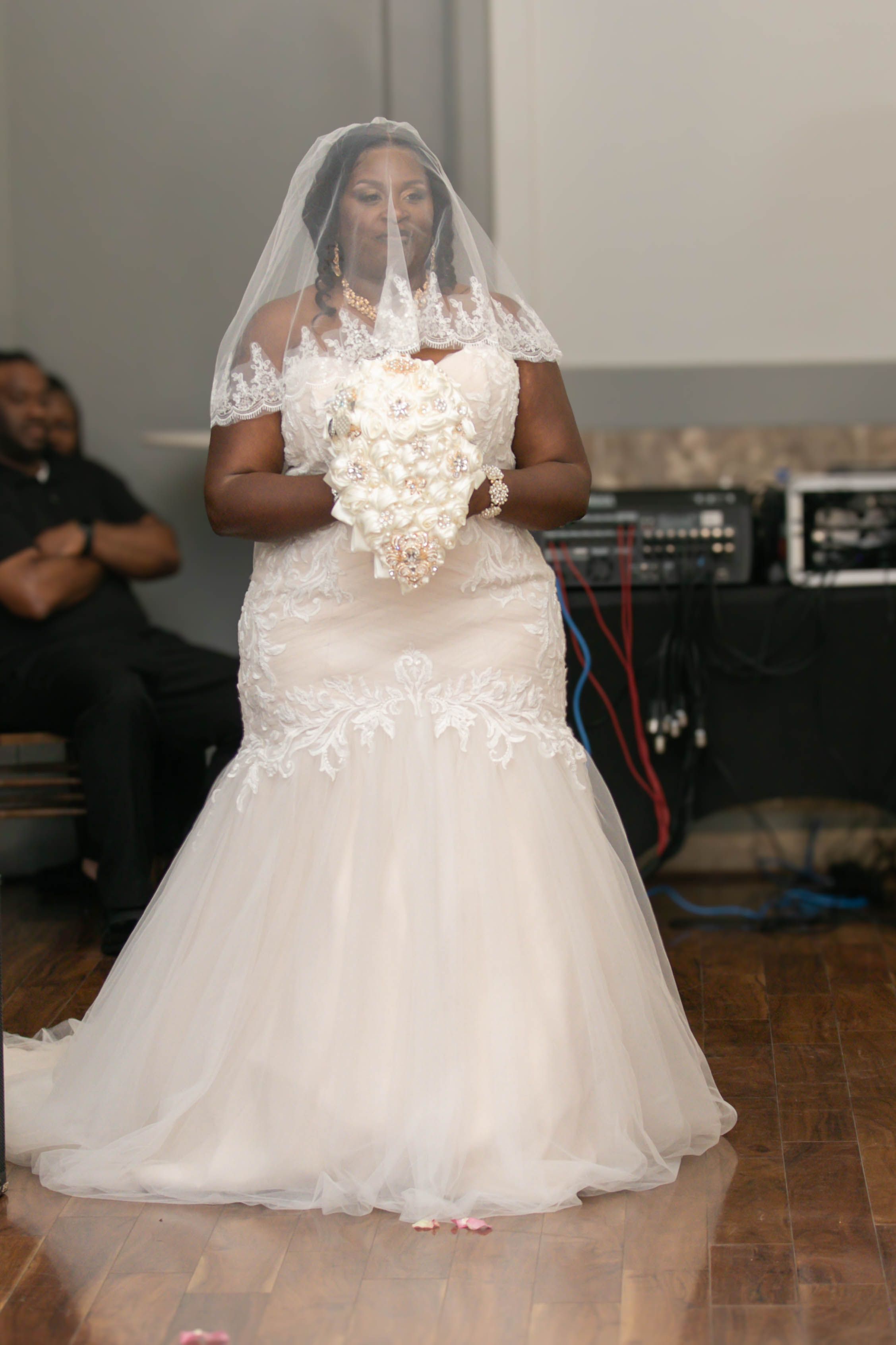 A bride wearing a stunning lace-detailed mermaid wedding gown during her ceremony.