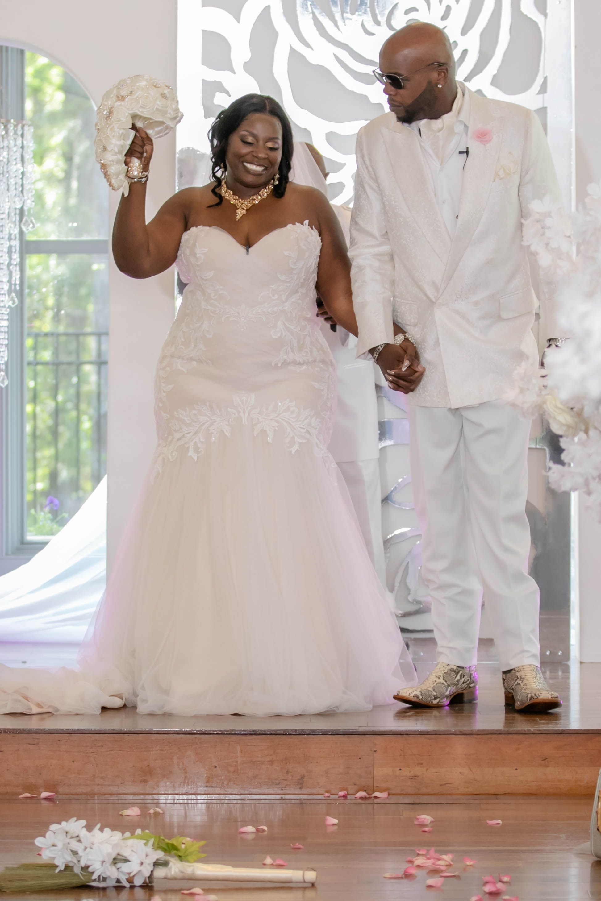 A couple celebrates during their wedding ceremony in matching white attire.