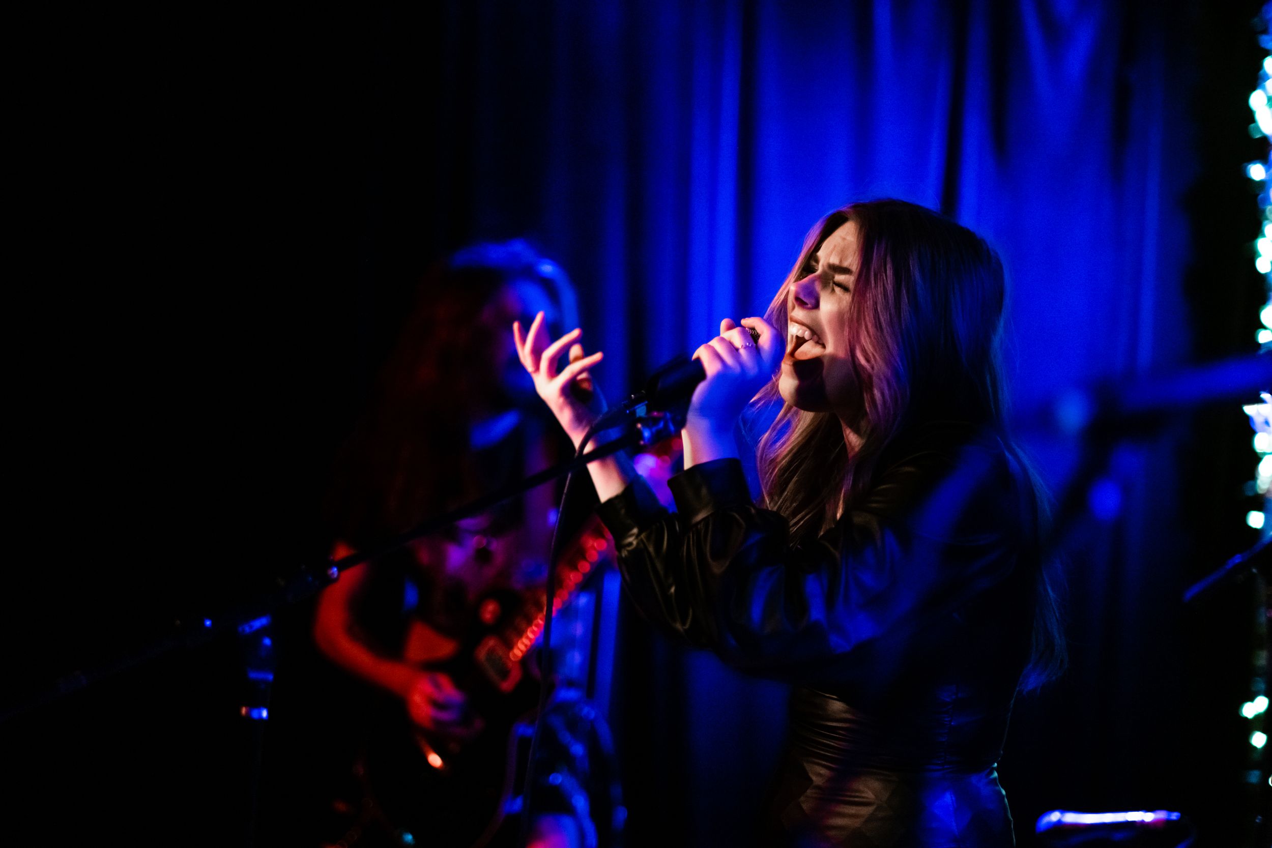 Singer performs emotively under blue stage lighting during concert.