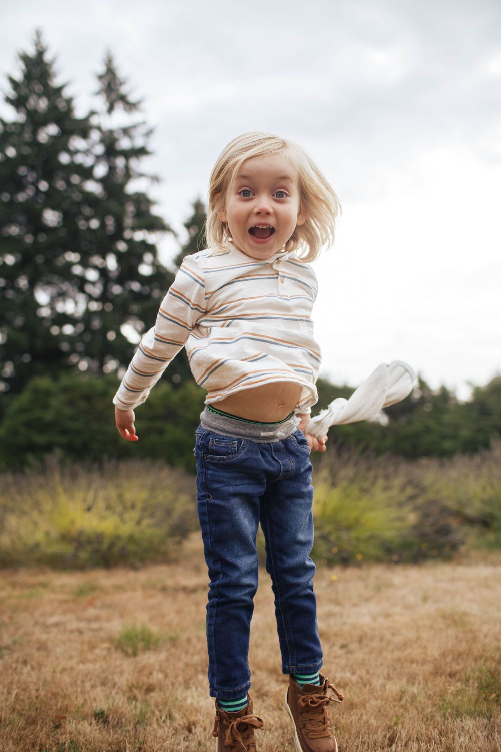 A young boy jumps in the air in a field at a family photography session