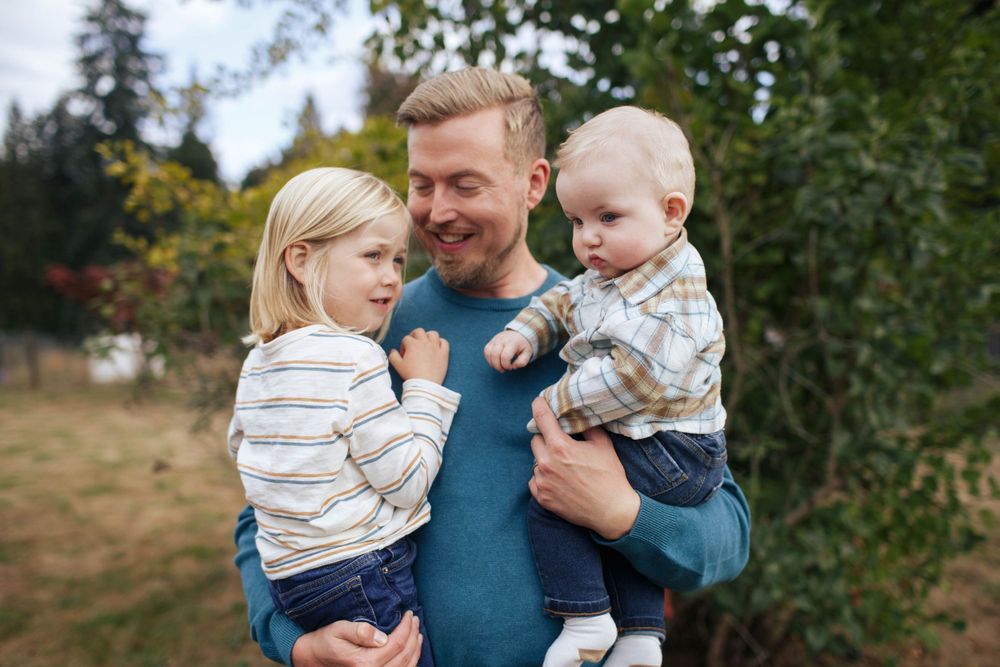 A father carries his newborn son and 3-year old at a family photo session in Snohomish WA