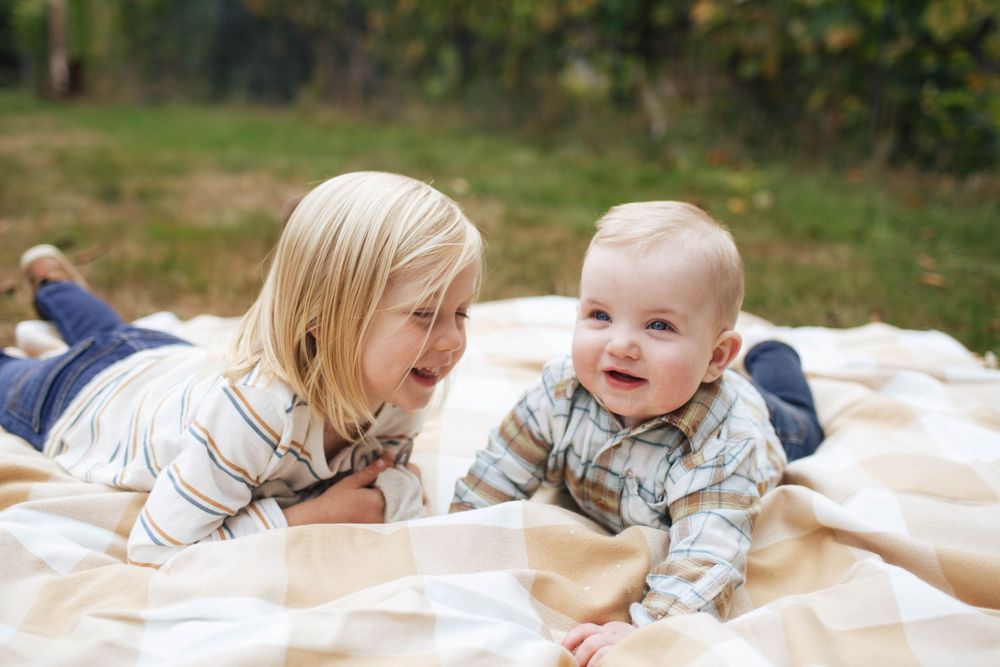 a 3-year-old boy lays on a blanket with his baby brother at a family photo session in Snohomish WA