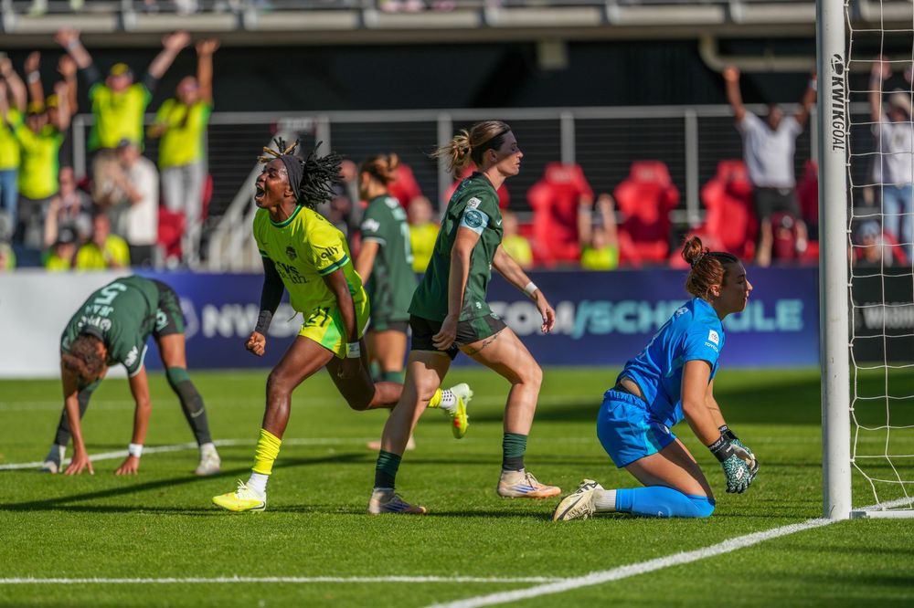 Soccer players diving and scrambling for the ball near the goal during an intense match.