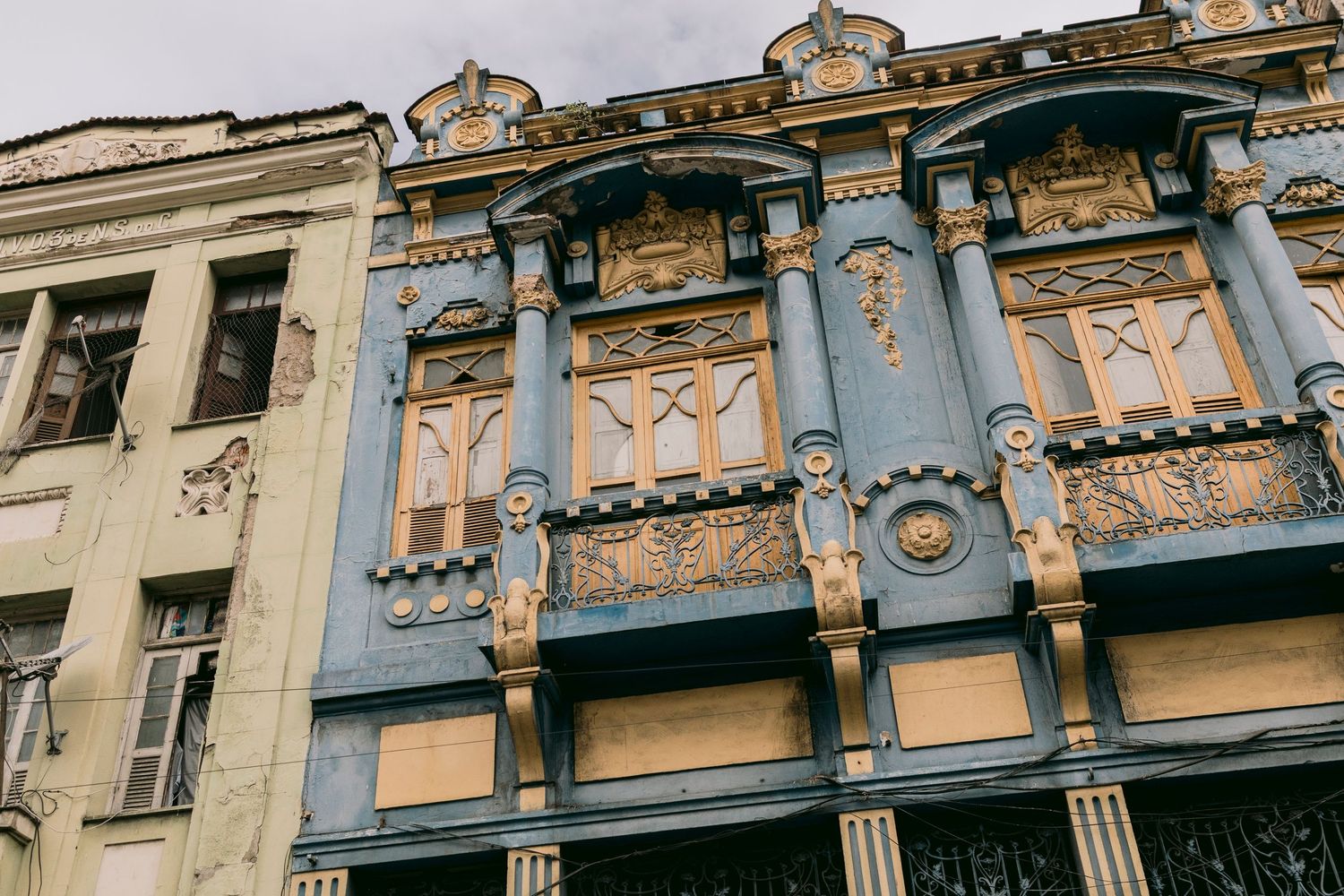 Ornate blue and gold Art Nouveau building facade with decorative sculptures and columns in historic city.