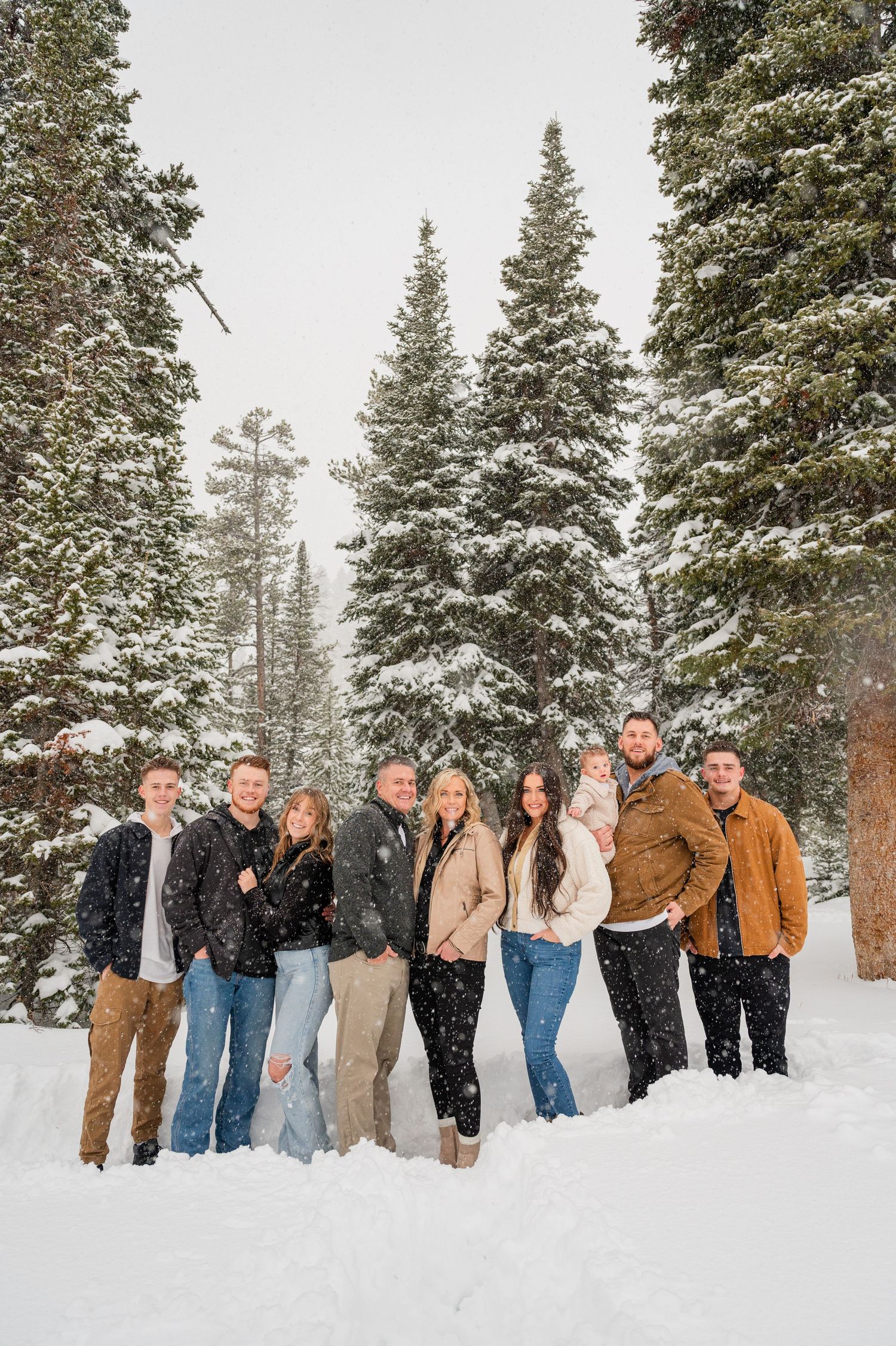 Group photo of people standing together in snow with tall evergreen trees in the background.