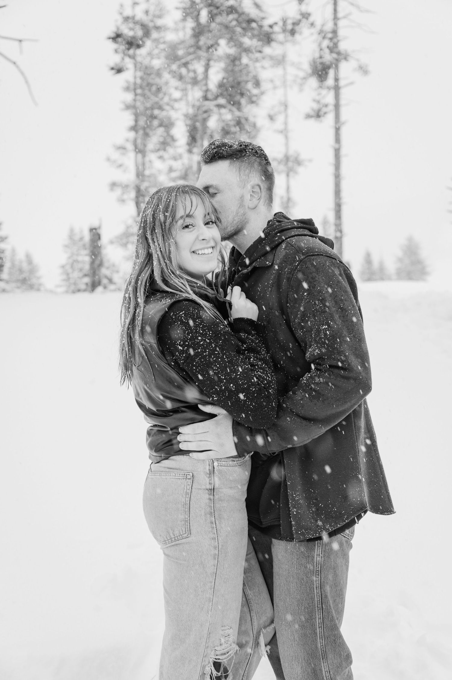 Romantic black and white portrait of couple embracing in snowy winter setting.