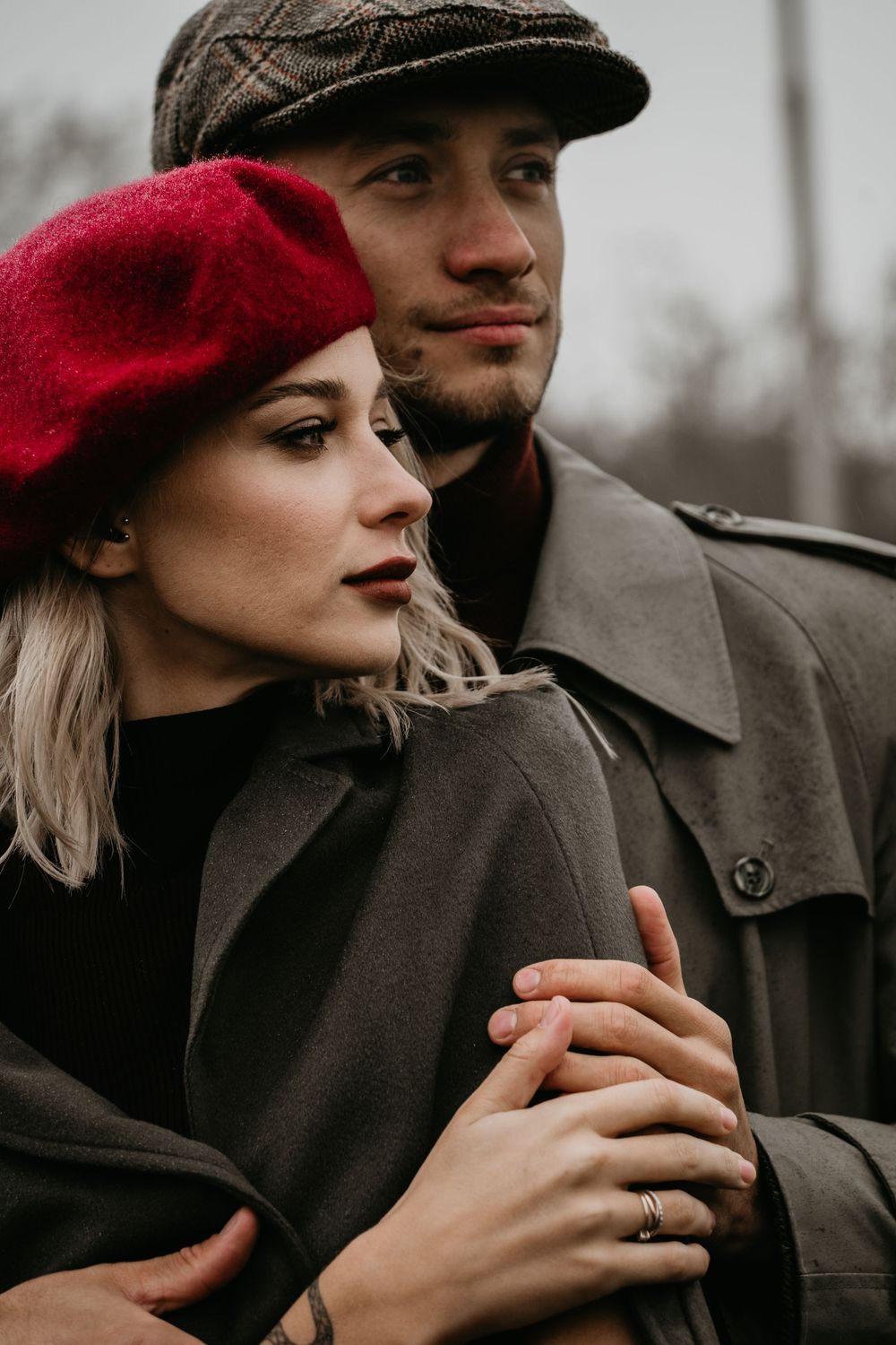 Woman in a red hat being embraced from behind by her partner