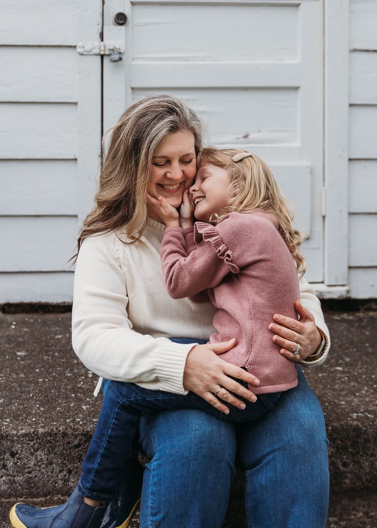 Sweet moment of closeness and giggles shared between child and adult sitting together against a white door.
