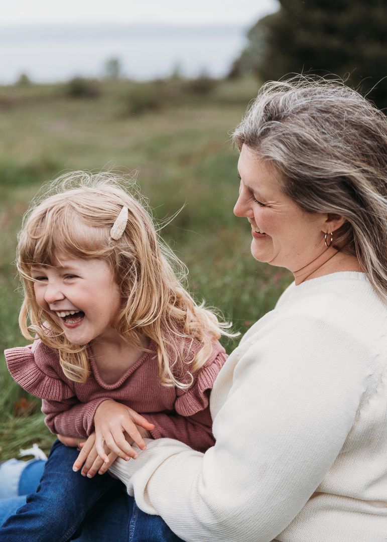 A joyful candid moment captured outdoors showing genuine laughter and connection between child and adult in casual wear.